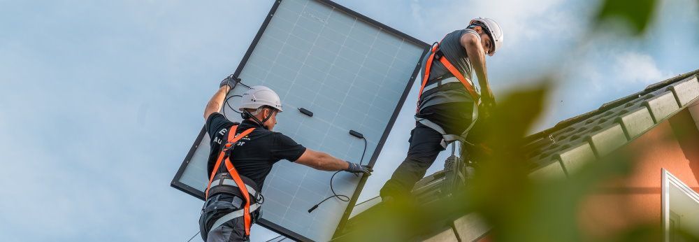 Zwei Männer in Sicherheitskleidung installieren ein Solarpaneel
